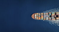 Aerial top down view of a large container cargo ship in motion over open ocean with copy space